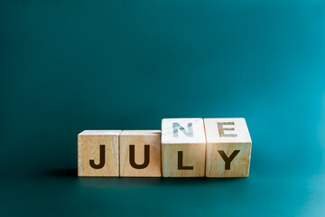 Poster - Changing the month of mid of the year. Flipping wooden cube blocks for change words, months from June to July, isolated on blue background with copy space, clean, modern, and minimal style.