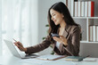 © Kritdanai - Asian businesswoman in formal suit in office happy and cheerful during using smartphone and working