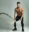 © Thurstan H/peopleimages.com - Work your muscles like never before. Studio shot of a young man working out with a heavy rope against a gray background.