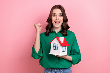 Sticker - Photo of charming lucky lady dressed green blouse rising fist holding small house isolated pink color background