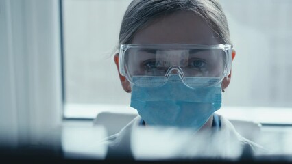 Aufkleber - A female researcher sits at a workplace in a laboratory, behind a personal computer monitor. Against the background research statistics. Pharmaceutical medical worker in protection works at keyboard.