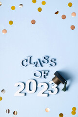 Class of 2023 concept. Wooden number 2023 with graduated cap on blue background with tinsel top view