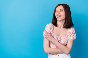Wall Mural - Photo portrait of cute young girl finger point offer look empty space dressed trendy flower print outfit isolated on blue color background