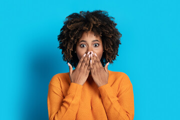 Wall Mural - Surprised emotional young black woman cover mouth looking at camera