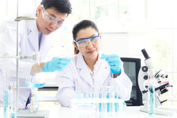 Wall Mural - team work asian woman and man scientists analyzing study data and evaluating microscope success for 