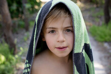 Young Boy Looking At Camera With Beach Towel Over His Head
