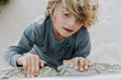 © Austockphoto - Close up shot of a boy climbing on a pile of rocks.