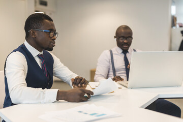 Two African American business partners are working on a laptop together on a common project. Coworking, social contacts and remote networking