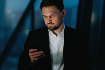 businessman use smart phone at night in office. a man with a phone in his hands