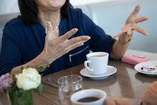 Senior Women Holding Hands, Laughing And Drinking Coffee In Cafe