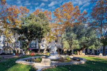 Wall Mural - Nimes city, in France, a pretty wooded square in the historic centre, typical buildings
