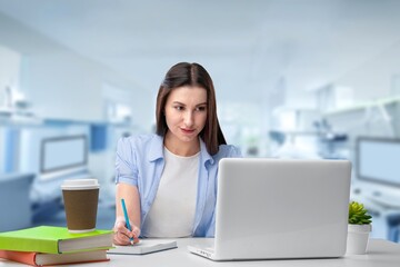 Canvas Print - Happy female student sitting at the desk with laptop