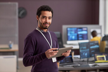 Wall Mural - Waist up portrait of smiling software engineer holding digital tablet while standing in tech office, copy space