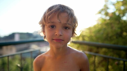 portrait of a happy child standing outdoors. one small boy with positive expression. close up blonde