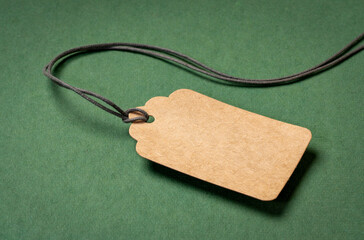 blank paper price tag with a twine against green, textured,  rag paper, shopping concept