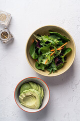 Wall Mural - Salad with leaf vegetables and sliced avocado in bowl on grey background