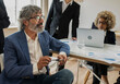 © PintoArt - coworkers in office, focus on boss gray-haired mature man
