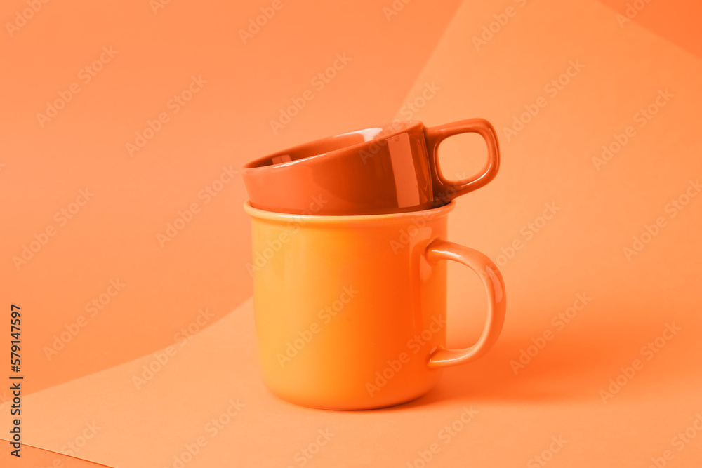 Ceramic mugs on color background