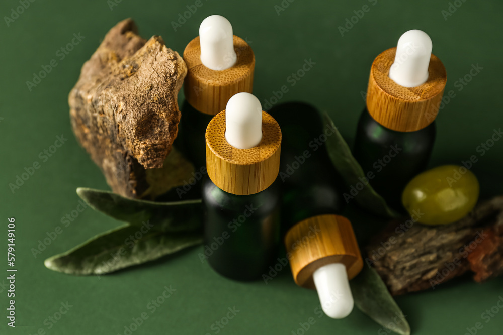 Bottles of olive essential oil on green background