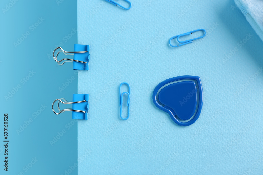 Sheet of paper with binder clips on color background