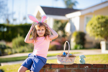 Child boy hunting easter eggs. Kid with easter eggs and bunny ears outdoor. Children activity for Easter in nature.