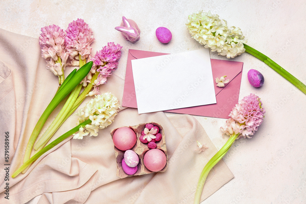 Composition with beautiful hyacinth flowers, blank greeting card and Easter eggs on beige background
