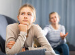 Sad female and daughter sitting at sofa and having quarrel at home