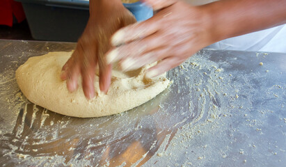 woman kneading tortilla dough on the stainless steel table