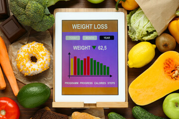 Wall Mural - Tablet with weight loss calculator application and food products on wooden table, flat lay