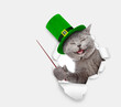 Saint Patricks Day concept. Funny cat wearing hat of the leprechaun looks through the hole in white paper and points away on empty space. isolated on white background. Space for text