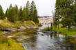 Scenic river with trees and a geyser in Yellowstone National Park