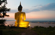 Big Golden Buddha Statue Enshrined On A Hill In Pakse, Laos, Overlooking The Mekong River And Pakse City During Twilight.