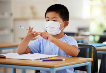 Poster - Education, covid and learning with face mask on boy doing school work in classroom, writing and counting at his desk in elementary class. Asian child wearing protection to stop the spread of virus