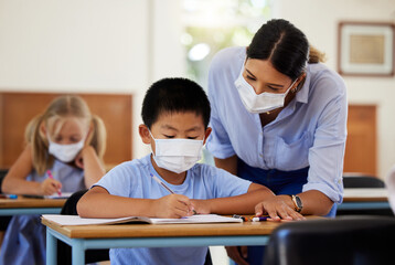 Poster - Covid, education and learning with a teacher wearing a mask and helping a male student in class during school. Young boy studying in a classroom with help from an educator while sitting at his desk.