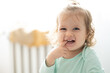 toddler girl smile and puts finger in mouth, authentic joy, bright concept