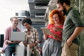 Diverse group of professionals meeting in office. IT programmers use computer, talk strategy