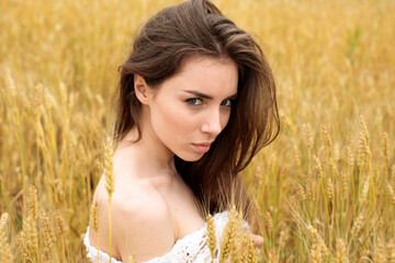 Wall Mural - Portrait of a young girl on a background of golden wheat field