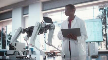 Poster - Young African American Male Engineer Testing Industrial Programmable Robot Animal in a Factory Development Workshop. Black Researcher in a Lab Coat Developing AI Canine Prototype, Using Laptop