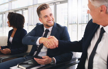 Poster - Hello Its a pleasure to meet you. Cropped shot of a handsome young businessman shaking hands with a colleague while sitting in a line in the office.