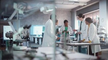 Leinwandbilder - Group of International Multiethnic Lab Specialists Gathering Around a Table to Discuss Blueprints and Components for a High Tech Robotic Project. Young Engineers Working in Company Facility Lab