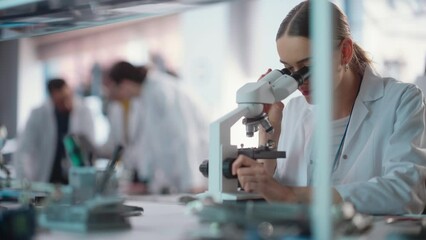 Poster - Diverse Young Group of Engineers Working in a Startup Lab. Project Managers Discuss Manufacturing Using Laptop Computer While Female Specialist Checking on Electronic Circuit Using Microscope