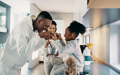 Wall Mural - Dad playing with his daughter while mom is cooking in the kitchen