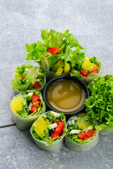 Wall Mural - Fresh rice paper rolls with avocado, cucumber, sweet pepper, lettuce and sauce.