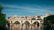 Village With A Roman Bridge Over A River On A Clear Day