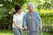 © amazing studio - Caregiver help Asian elderly woman patient walk with walker in park, healthy strong medical concept.