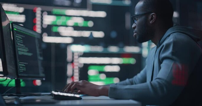 Fototapete - Dolly Shot of a Black Male Programmer Working in a Monitoring Control Room, Surrounded by Big Screens Displaying Lines of Programming Language Code. Portrait of a Man Creating a Software and Coding