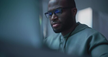 Wall Mural - Close Up Portrait of Black Man Working on Computer, Lines of Code Language Reflecting on his Glasses. Male Programmer Developing New Software, Managing Cybersecurity Project. Slow Motion