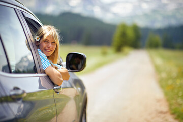 beautiful blonde woman smiling with flower in her hair. rear view of car on the road. transport, roa