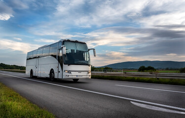 white modern comfortable tourist bus driving through highway at bright sunny sunset. travel and coac