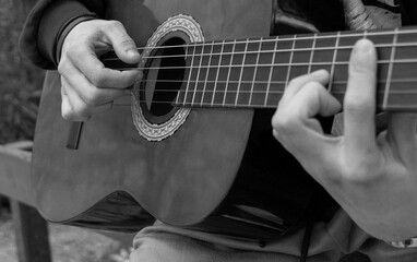 boy's hands playing an spanish guitar in the open air